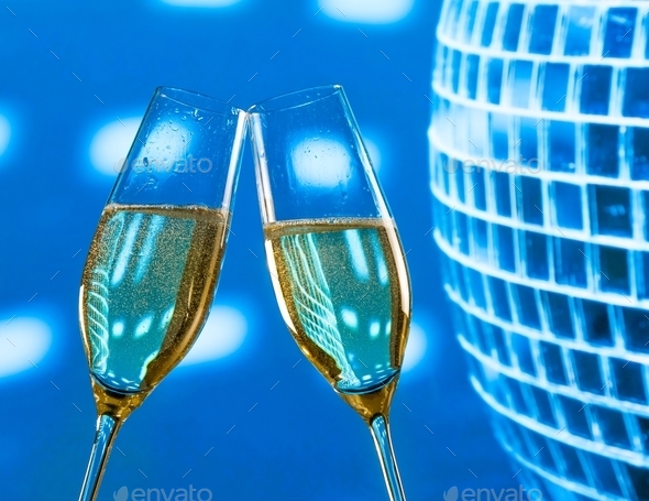 a pair of champagne flutes with golden bubbles make cheers on sparkling blue disco ball background