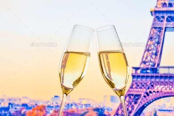 a pair of champagne flutes with golden bubbles on blur tower Eiffel background