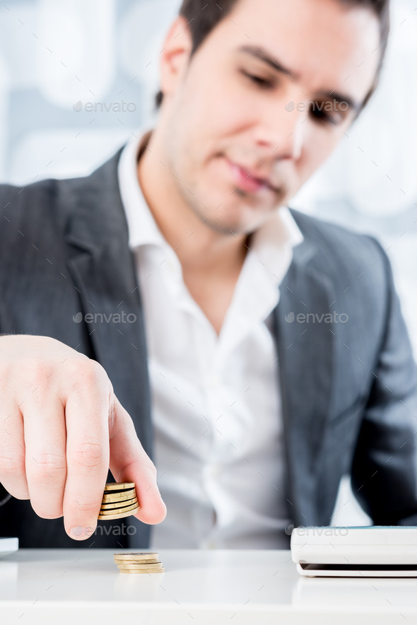 Businessman sitting at his desk counting Euro coins
