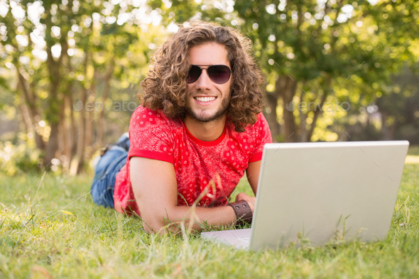 Handsome hipster using laptop in the park on a sunny day (Misc) Photo Download