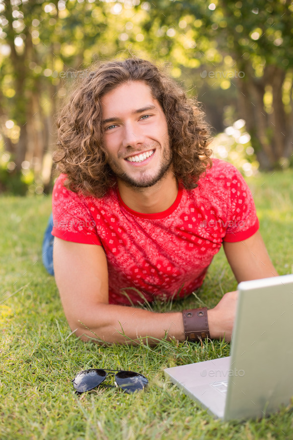 Handsome hipster using laptop in the park on a sunny day (Misc) Photo Download