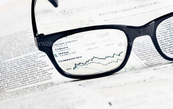 financial chart and graph currencies see through glasses lens on financial newspaper
