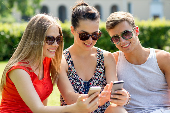 smiling friends with smartphones sitting in park (Misc) Photo Download