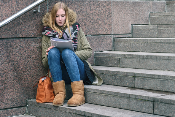 Young woman sitting reading on urban steps