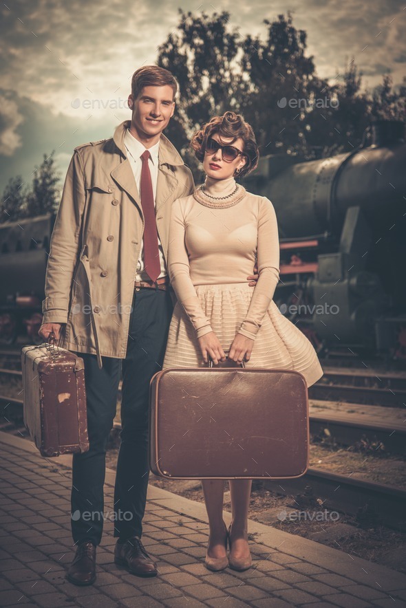 Beautiful vintage style couple with suitcases on train station platform