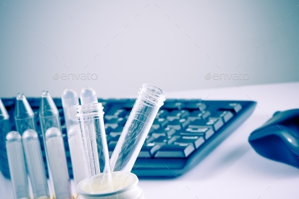test tubes in laboratory on table near computer keyboard and mouse