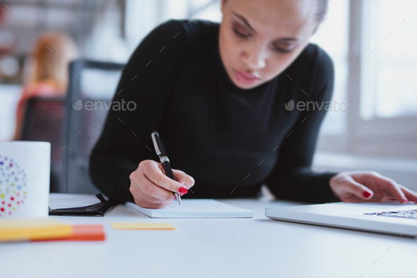 Young woman at her desk taking note