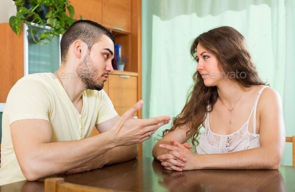 Serious young couple talking at home