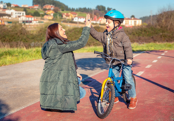 Mother and son giving five by success riding bicycle