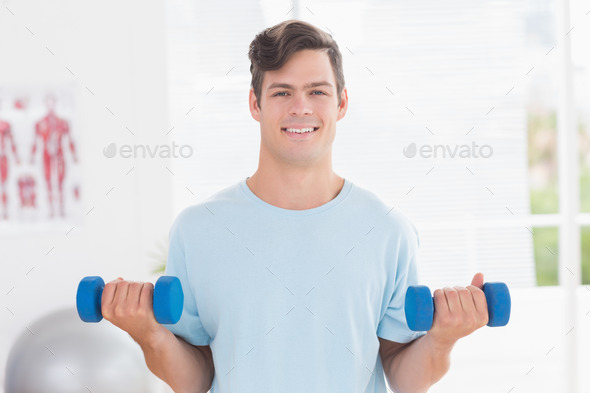 Young man training with dumbbells in medical office (Misc) Photo Download