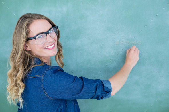 Smiling geeky teacher writing on blackboard in classroom (Misc) Photo Download