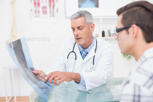 Doctor showing Xrays to his patient in medical office (Misc) Photo Download