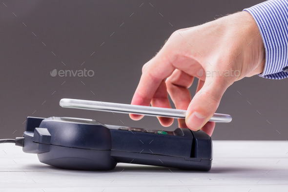 Man using smartphone to express pay against grey background (Misc) Photo Download