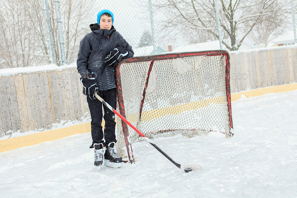 teenager playing hockey outside on a ice rink.
