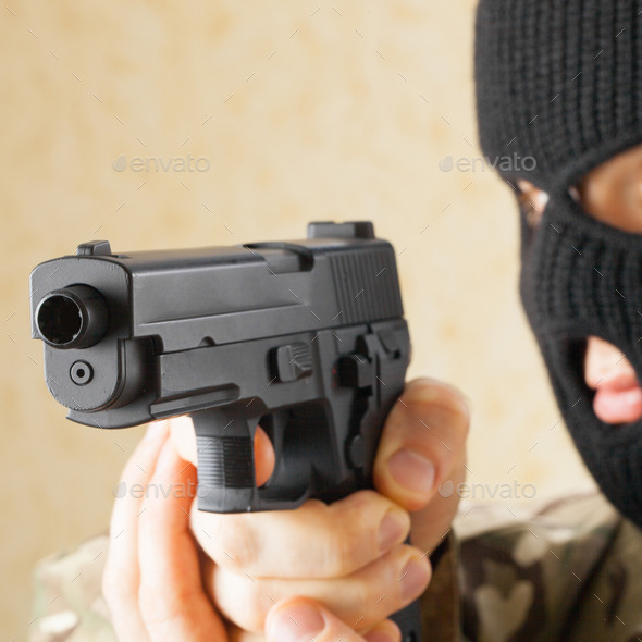 Man in black mask holding gun before him