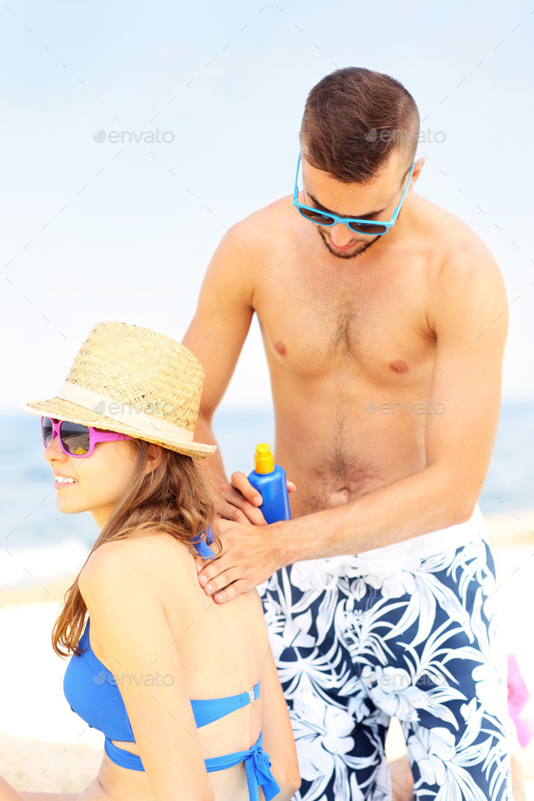 Man applying sunscreen on the back of his woman