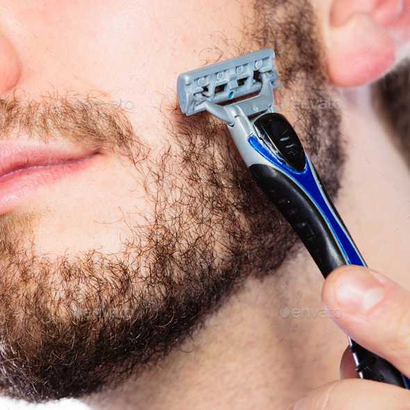 Young man with beard holding razor blade