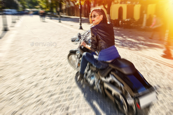 Biker girl in a leather jacket riding a motorcycle