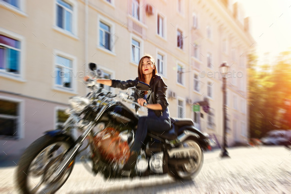 Biker girl in a leather jacket riding a motorcycle
