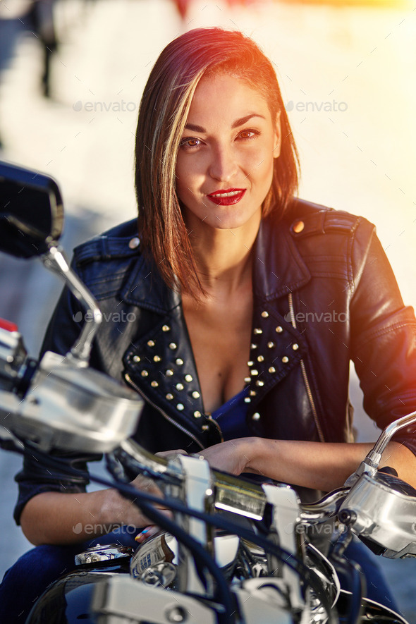 Biker girl in a leather jacket on a motorcycle