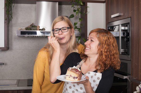 Delighted girlfriends eating cake in the kitchen (Misc) Photo Download