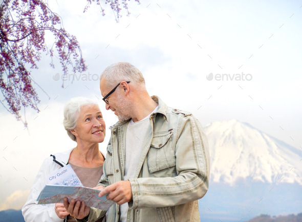 happy senior couple with travel map over mountains