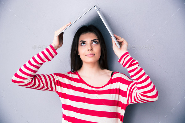 Woman holding a laptop above her head like a roof