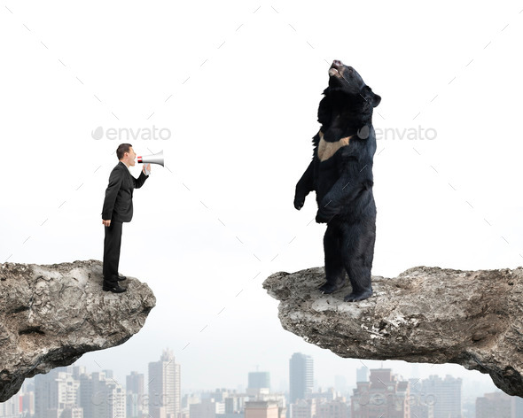 Businessman yelling at black bear on cliff with cityscape (Misc) Photo Download