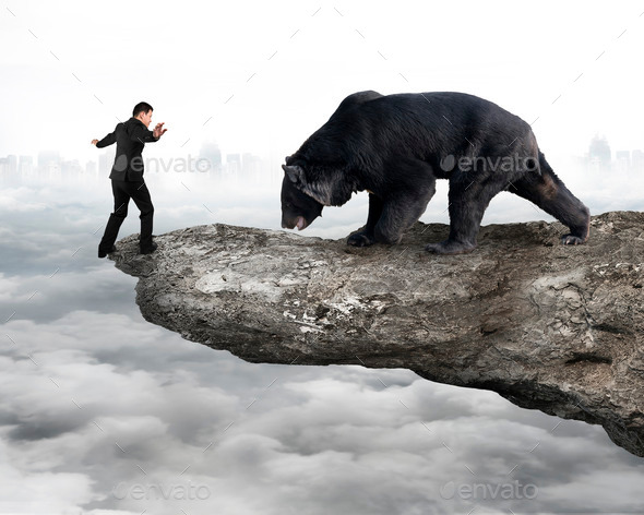 Businessman against black bear balancing on cliff with cloudy sky (Misc) Photo Download