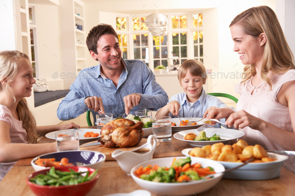 Happy family having roast chicken dinner at table (Misc) Photo Download