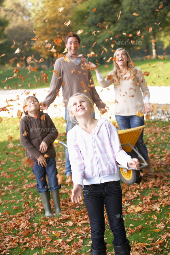 Family throwing autumn leaves into the air in garden (Misc) Photo Download