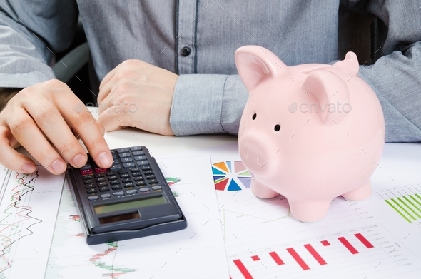 Man calculates money. Piggy bank and business documents on desk (Misc) Photo Download