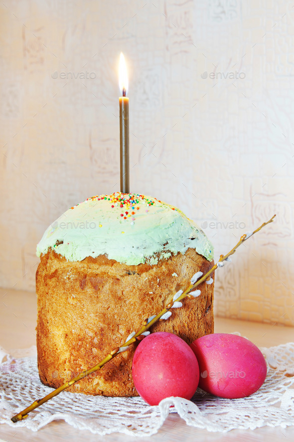 Orthodox Christian Easter still life with red eggs and burning candle over the cake