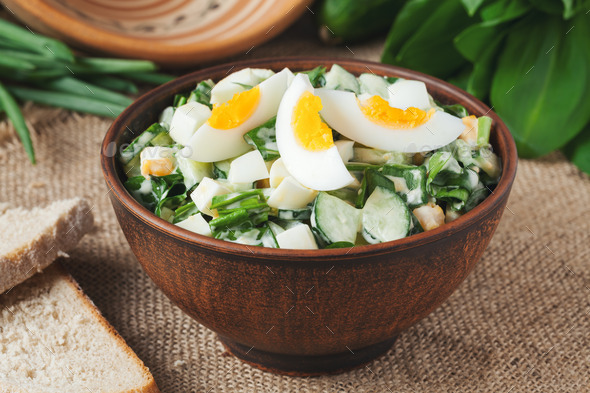 Green spring salad with chopped garlic and ramson served in rustic bowl