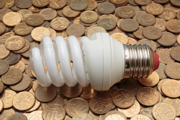 Energy saving light bulb on coins background (Misc) Photo Download