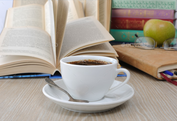 A cup of coffee on the table against the background of an open b (Misc) Photo Download