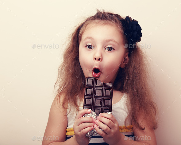 Surprised girl with open mouth holding chocolate and looking