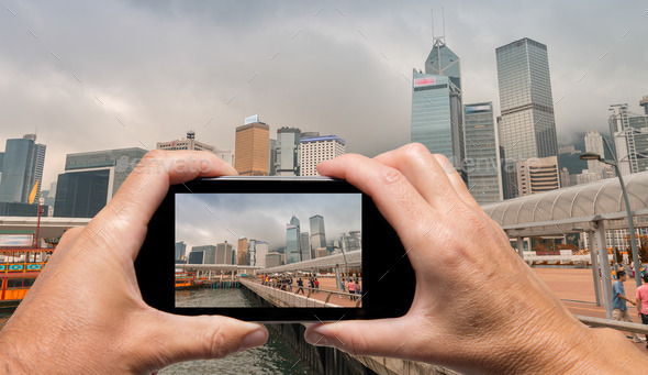 Man and woman hand capturing Hong Kong skyline with smartphone