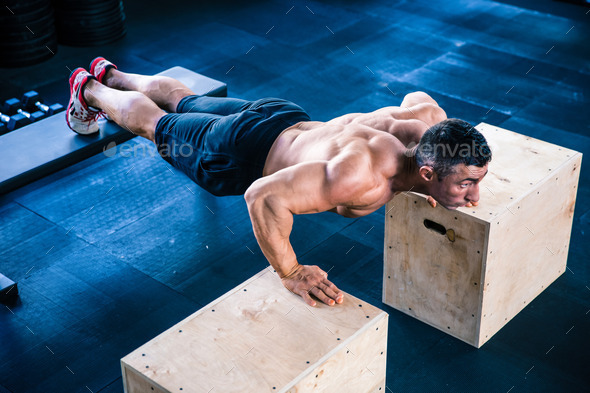Muscular man doing push ups on fit box