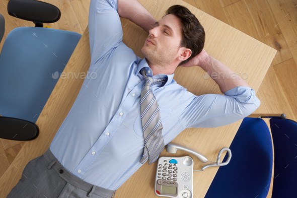Overhead View Of Businessman Lying On Desk In Office