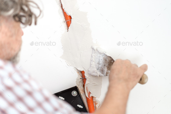 Electrician plastering recessed wiring in a wall