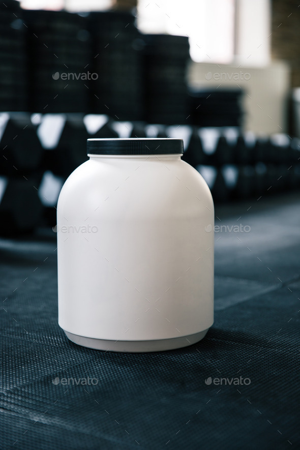 Plastic container with sports nutrition on dumbbells