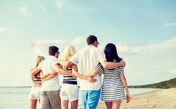 smiling friends hugging and walking on beach (Misc) Photo Download