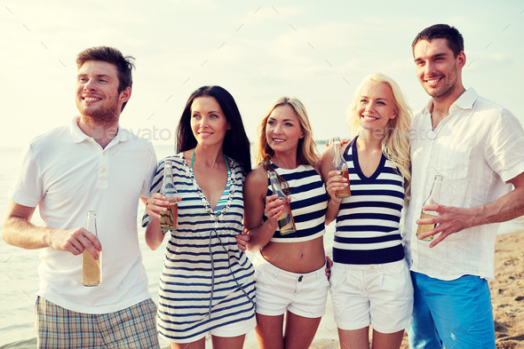 smiling friends with drinks in bottles on beach (Misc) Photo Download