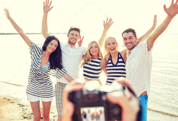 friends on beach waving hands and photographing (Misc) Photo Download