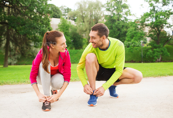 smiling couple tying shoelaces outdoors (Misc) Photo Download