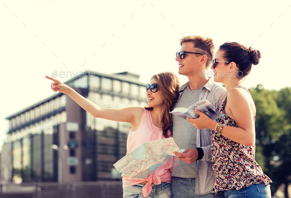 smiling friends with map and city guide outdoors