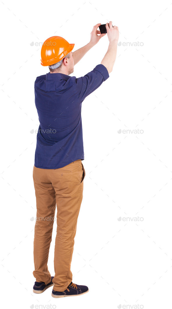 Backview of an engineer in construction helmet stands and using (Misc) Photo Download