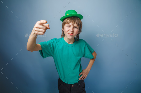 Boy teenager European appearance in green hat shows his finger f