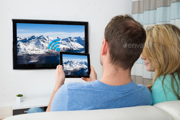 Couple With Digital Tablet And Television In Room
